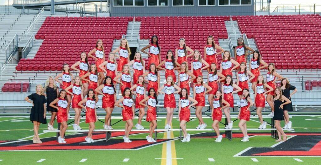 Cheerleading team posing on football field for team photo.