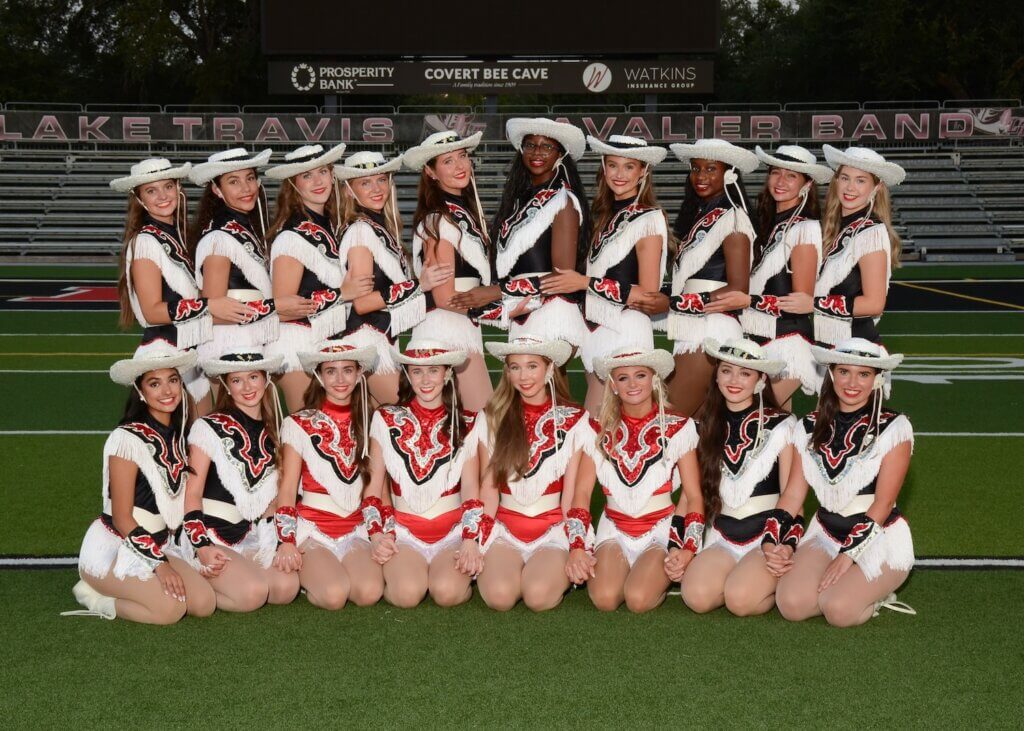 Dance team seniors dressed in uniform and lined up on the football field.